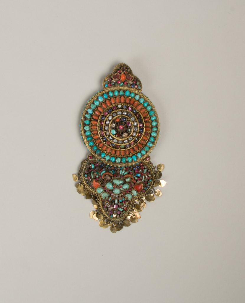 Historical Tibetan earring with circular and pendant sections set with colorful stones, photographed by The Metropolitan Museum of Art.